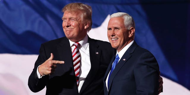Donald Trump and Mike Pence pose together on a stage. 