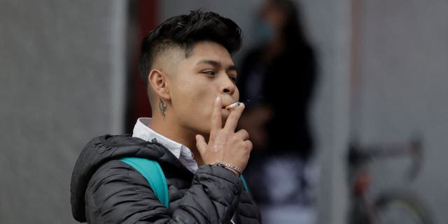 A young man smokes a cigarette in the streets of Mexico City during World No Tobacco Day in Mexico.