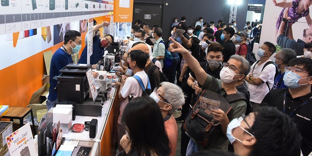 People wearing face masks shop for Solid State Drive (SSD) during the Hong Kong Computer and Communications Festival 2021 at Hong Kong Convention and Exhibition Center on Aug. 20, 2021, in Hong Kong, China.