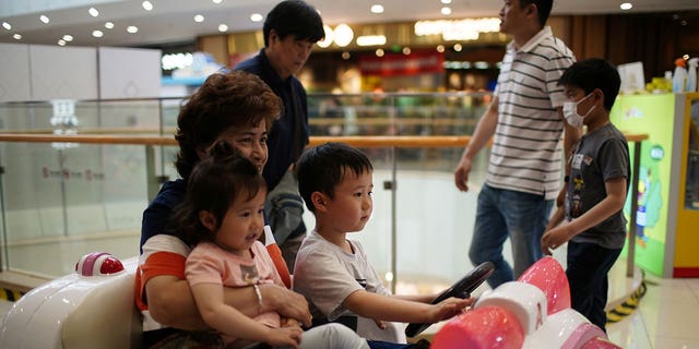 A person holds a girl as a boy drives a toy car at a shopping mall in Shanghai, China, on June 1, 2021. 