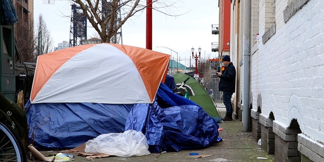 Kevin Dahlgren, a drug and alcohol counselor, stands near a row of tents on a Portland sidewalk on Feb. 17, 2023.