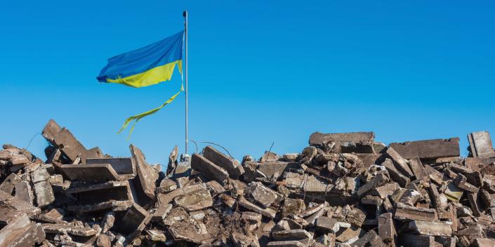 Ukraine flag over rubble.