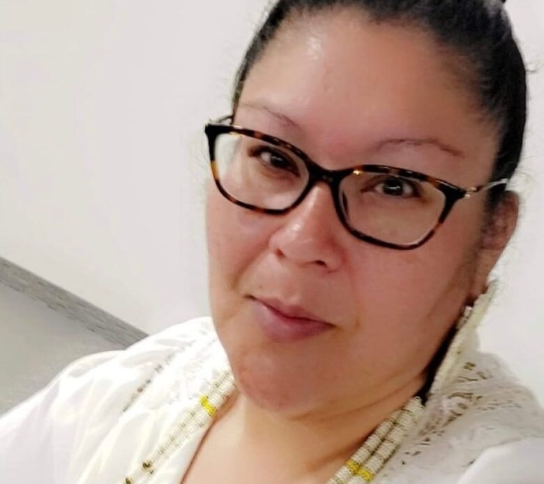 A woman with a bun and glasses smiles at the camera