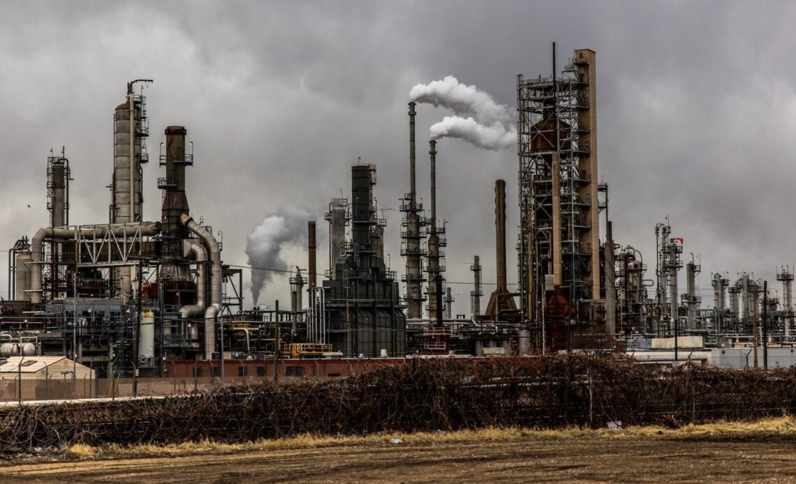 Image of an oil refinery with smoke stacks.