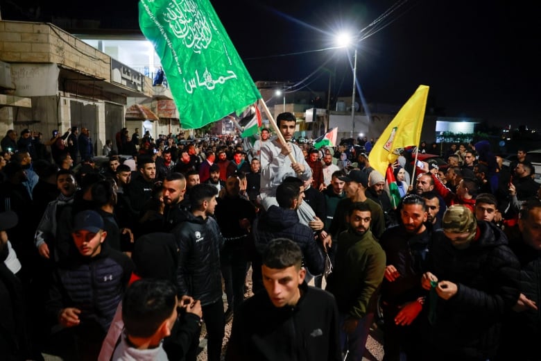 Palestinians released from a military prison are carried by a crowd as they hold flags.