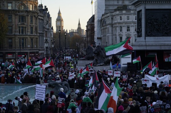 Protester hold flags and placards as they take part in a pro-Palestinian demonstration in Trafalgar Square in London, Saturday, Nov. 25, 2023. (AP Photo/Alberto Pezzali)