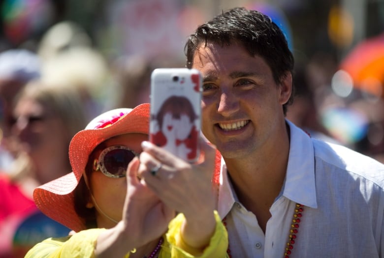 A woman uses her phone to take a photo of herself with Liberal leader Justin Trudeau during the Vancouver Pride Parade in Vancouver, B.C., on Sunday August 3, 2014. Organizers expected more than half a million people to take in the parade which is one of the largest in North America.