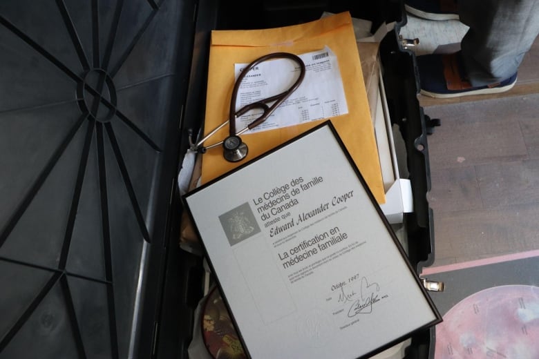 A bin filled with personal items. A medical degree and stethoscope lay on top.