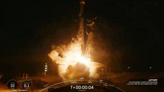 a black-and-white spacex falcon 9 rocket launches into a night sky.