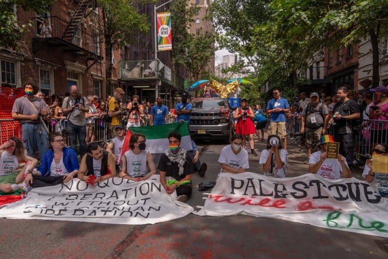 Demonstrators sit on and block a street during a protest.