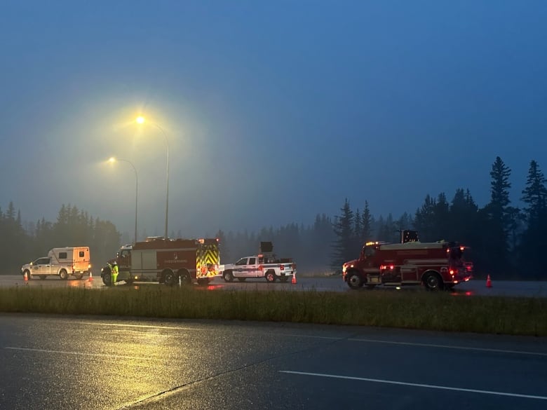 Red fire trucks on a road in the morning sunrise.