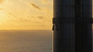 closeup of the side of a silver rocket booster, with the sun setting over the ocean in the background