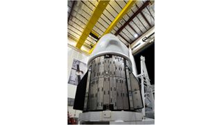 a white space capsule inside a hangar at night