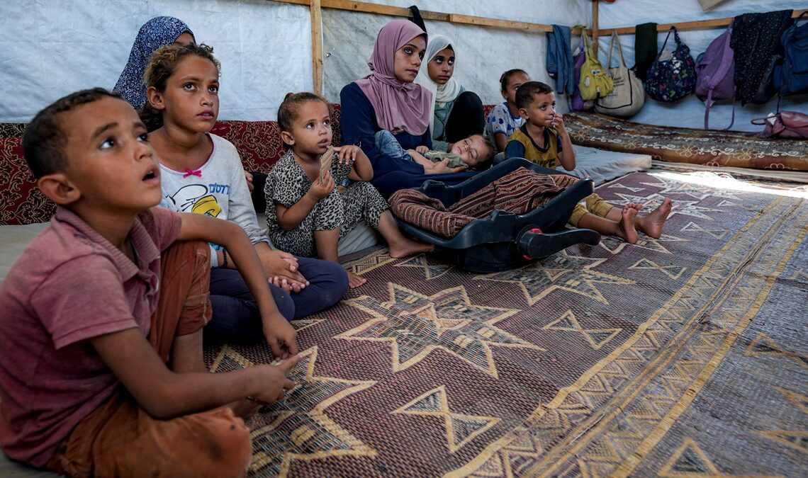 Displaced Gazans gather in a tent camp in Deir al-Balah.