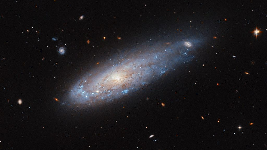 Distorted galaxy whizzes through crowded cluster in new Hubble image