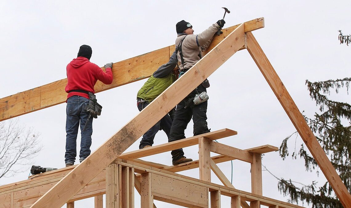 workers frame roof of house