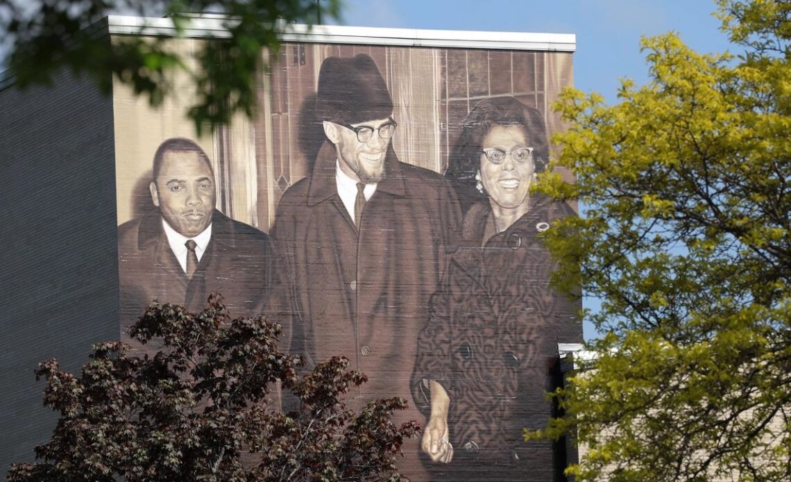 Rev. Franklin Florence and Constance Mitchell flank Malcolm X in a mural painted on the side of East High School in Rochester.