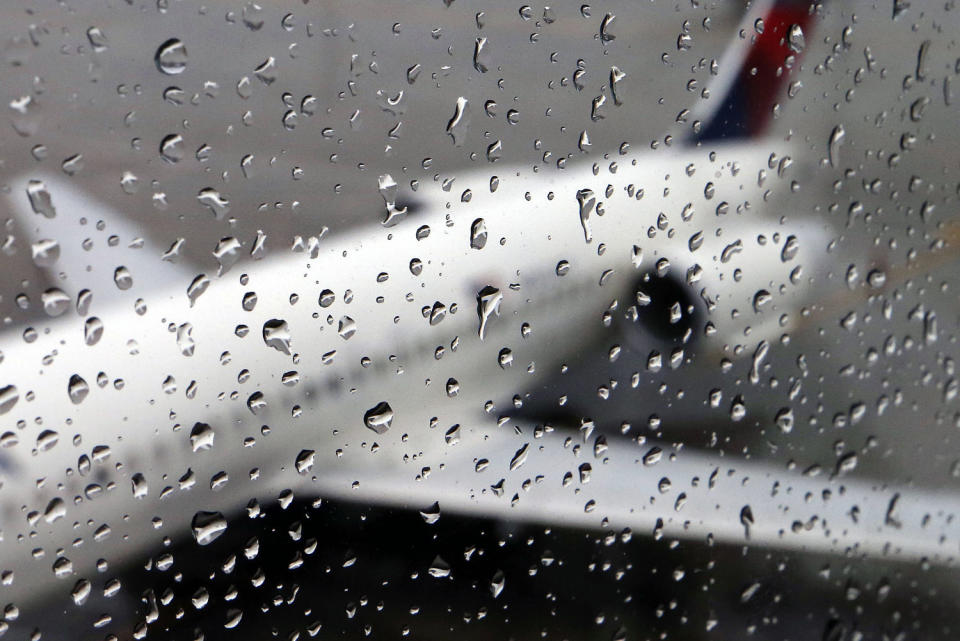 A plane sits on the tarmac behind rain drops on a window (Michael Dwyer / AP)