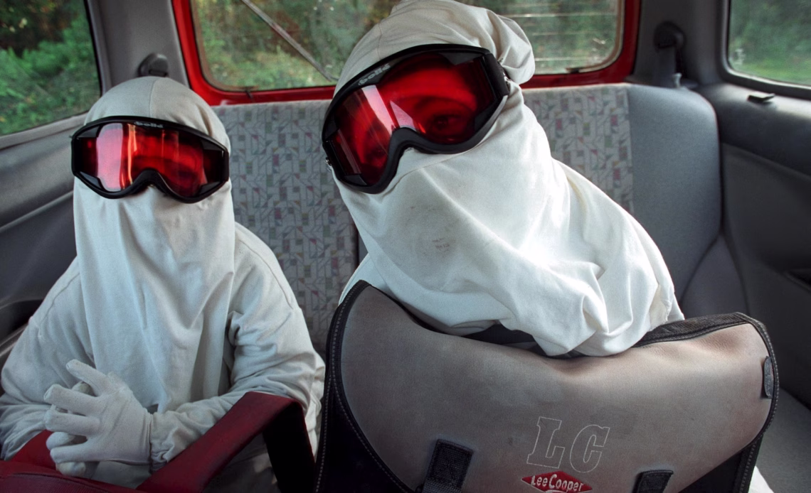 two children wearing cloth over their face, ski goggles, and gloves