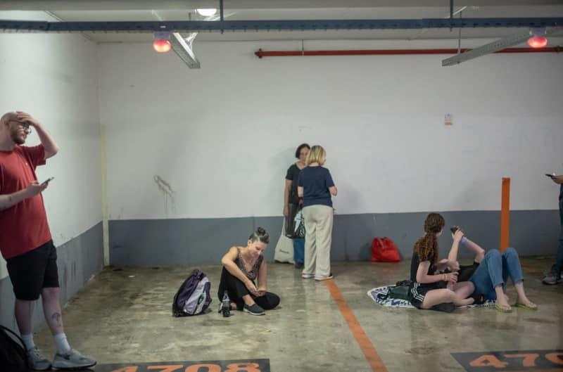 People seek shelter as sirens sound during a missile strike in Ramat Gan, near Tel Aviv, where several cars and buildings were destroyed. The attack was part of a large-scale Iranian missile barrage on June 13, launched in retaliation for Israeli strikes on senior military officials and strategic sites in Iran. Ilia Yefimovich/dpa