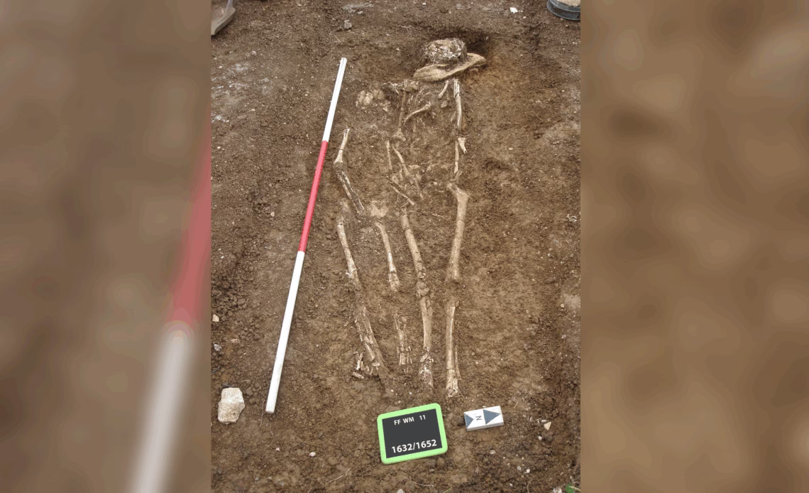 Two human skeletons lie side-by-side in an excavated grave